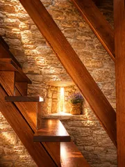 Scala in legno dell'appartamento Dazio con muro in pietra e finestrella
